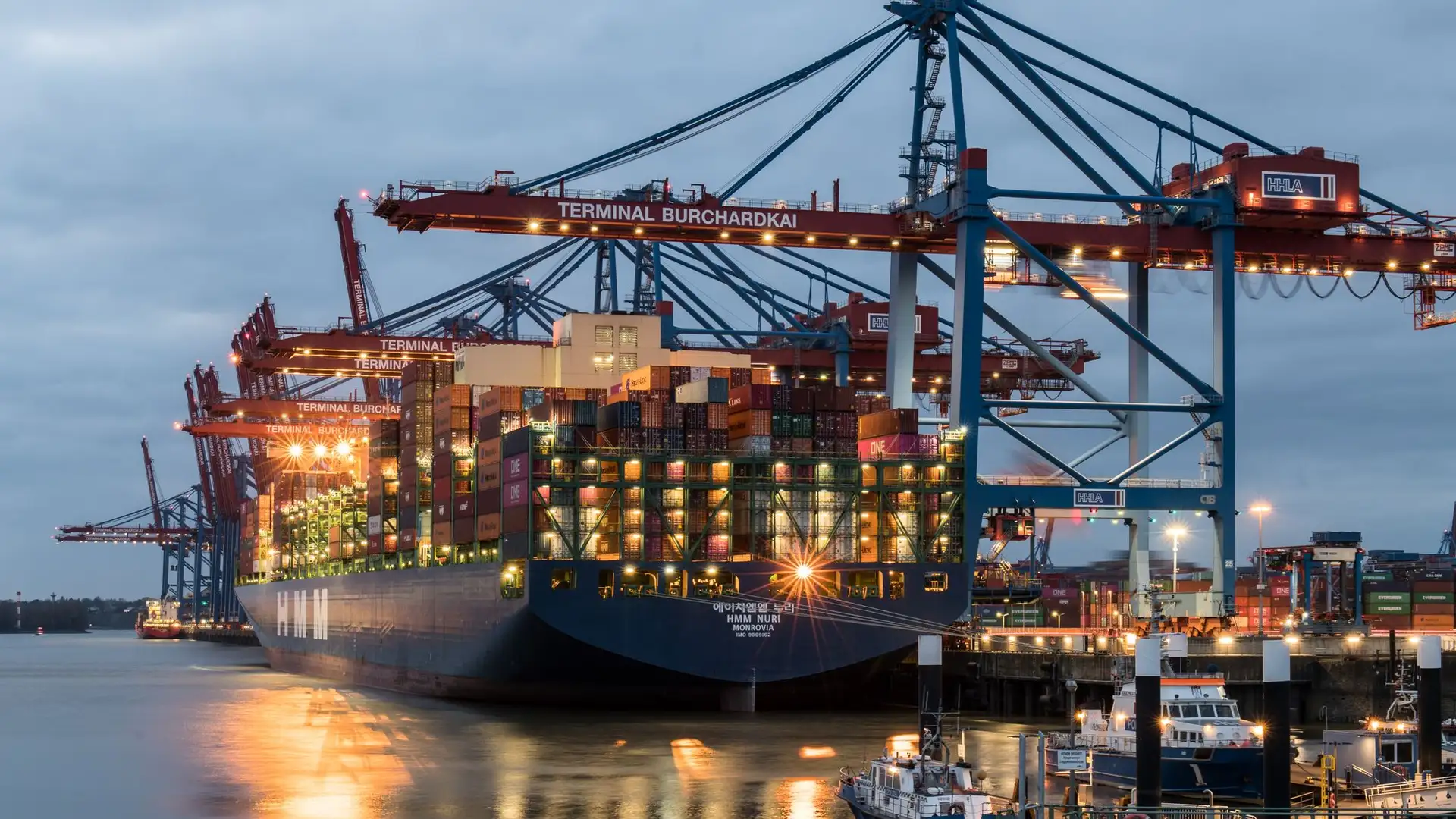 Container ship loading at a port terminal at dusk
